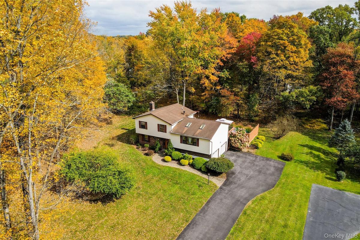 Split-level residence featuring a multi-tone exterior, asphalt driveway, two attached garage bays, roof-mounted skylights, and a wood privacy fence