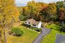 Split-level residence featuring a multi-tone exterior, asphalt driveway, two attached garage bays, roof-mounted skylights, and a wood privacy fence