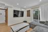 Light-toned wood-finish flooring, recessed lighting, wall-mounted ductless heating and cooling unit, and glass sliding door opening to an exterior bal