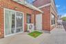 Exterior terrace featuring red brick masonry, tile flooring, a metal railing, and a sliding glass door
