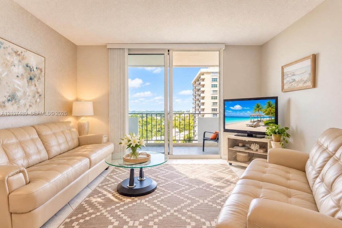 Living area featuring sliding glass doors leading to a private balcony with metal railings and neutral tile flooring