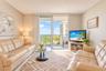 Living area featuring sliding glass doors leading to a private balcony with metal railings and neutral tile flooring