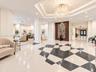 Grand lobby featuring geometric patterned terrazzo flooring, a coffered tray ceiling, a central crystal chandelier, and a decorative wood-paneled acce