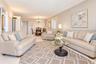 Neutral-toned interior space featuring light-colored tile flooring, overhead recessed lighting, and a multi-light chandelier fixture