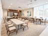 Spacious common room featuring floor-to-ceiling windows with sheer drapery, recessed ceiling lighting, dual ceiling fans, wood-paneled accent wall, an