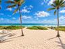 Direct beach access featuring expansive sandy terrain, mature palm trees, and native coastal vegetation