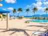 Paver pool deck with a swimming pool, shaded structural pavilions, and ocean backdrop