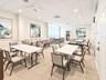 Spacious room featuring neutral carpeting, a drop ceiling with recessed lighting, integrated ceiling fans, and floor-to-ceiling windows