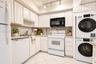 Kitchen featuring white cabinetry, solid-surface countertops, tile flooring, track lighting, and a built-in laundry unit