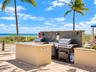 Outdoor kitchen featuring a stone-tile backsplash, stainless steel grill, stone-topped island, and paver-stone patio