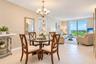 Open-concept space featuring neutral textured wall treatments, large-format tile flooring, a multi-arm chandelier, and floor-to-ceiling glass sliding 