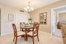 Dining area featuring textured wall finish, ceramic tile flooring, a multi-light metal chandelier, and a louvered-door storage closet