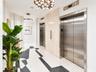 Elevator lobby featuring stainless steel doors, stone-tiled accent wall, geometric terrazzo flooring, and modern multi-bulb chandeliers