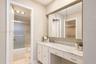 Vanity featuring a stone-look countertop, integrated sink, built-in medicine cabinet, and a dedicated seated vanity space, complete with a separate ar
