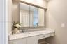 Vanity featuring a stone-patterned countertop, integrated basin with a chrome faucet, tri-fold mirrored medicine cabinet, and built-in drawers