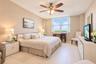 Spacious interior featuring large windows, neutral wall finishes, tile flooring, and a ceiling fan with integrated lighting