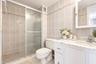 Bathroom featuring a shower with a sliding glass door, white vanity with stone-finish countertop, undermount sink, and tiled wall surround