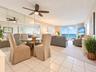 Open-concept living space featuring ceramic tile flooring, full-wall mirrored closet, ceiling fan with integrated lighting, and floor-to-ceiling slidi
