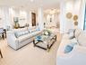 Open-concept common area featuring high ceilings, structural columns, intricate chandelier lighting, and a patterned stone floor