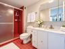 Vanity with stone countertop and integrated oval sink, built-in medicine cabinet, walk-in shower with textured glass door, and tiled flooring