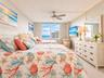Bedroom featuring a large multi-pane window with water outlook, carpeted flooring, and a ceiling-mounted light fixture with integrated fan