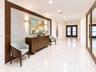 Polished stone flooring, wood-framed wall detailing, recessed ceiling lighting, and brass-finish wall-mounted sconces