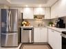 Kitchen featuring white cabinetry, stainless steel French door refrigerator, stainless steel dishwasher, solid-surface countertops, and recessed light