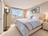 Neutral-toned interior space featuring neutral wall paint, wall-to-wall carpeting, and a large multi-pane window with a roller shade