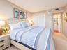 Neutral wall tones featuring carpeting, a double-door louvered closet, and an entry to an en-suite bathroom with a vanity