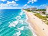 Coastal aerial perspective featuring sandy shoreline, turquoise ocean waters, and direct beach access