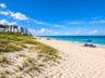 Direct oceanfront access featuring expansive sandy beach, coastal dunes with native vegetation, and panoramic sea scenery