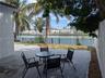 Concrete patio with metal fencing overlooking a canal, mature palm trees, and a white privacy fence