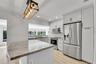 Kitchen featuring a curved peninsula island with a polished countertop, stainless steel appliances, light wood-finish flooring, white shaker-style cab