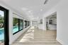 Bright interior with wood-finish flooring, recessed lighting, expansive windows overlooking a pool, and an open-concept kitchen featuring an island wi