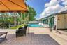 Paved patio with an integrated swimming pool, artificial turf, and waterfront access