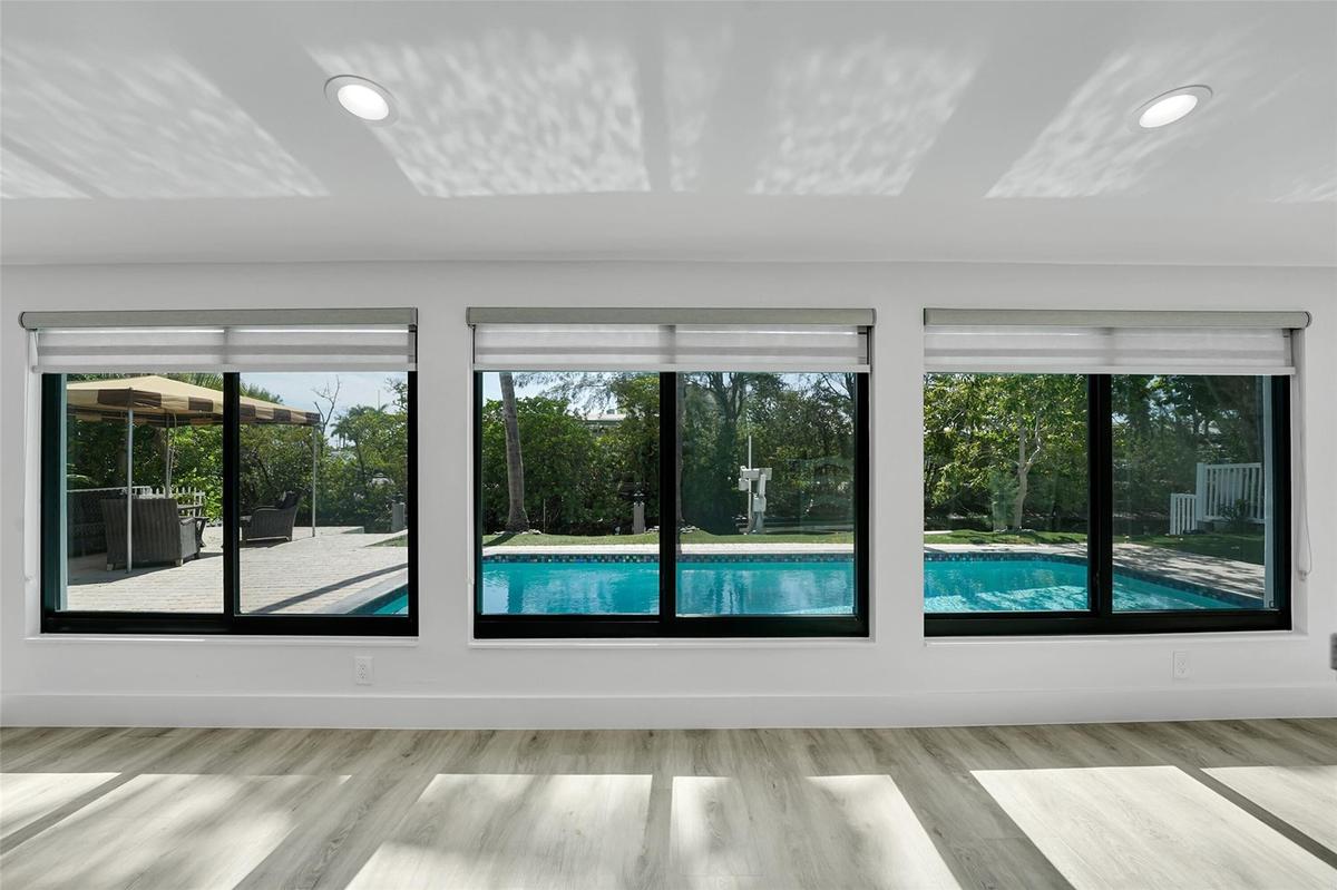 Light wood-finish flooring, recessed ceiling lighting, roller shades, and a swimming pool