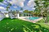 Expansive backyard featuring a rectangular swimming pool, paver deck, artificial turf, and privacy fencing