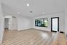 Recessed lighting, light wood-finish flooring, white walls, arched doorway, and a modern entry door with frosted glass