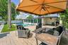 Expansive brick paver patio with a shaded canopy featuring a ceiling fan, offering direct access to the inground swimming pool