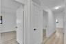 Wood-finish flooring throughout, bright white walls, and contemporary flush-mount lighting fixtures