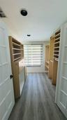 Walk-in closet with custom built-in shelving, drawers, wood-finish flooring, and recessed lighting