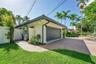 Attached garage with a panel-style door, brick paver driveway, and a manicured lawn