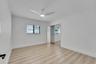 Spacious room featuring wood-finish flooring, a contemporary ceiling fan, and mirrored closet doors
