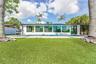 Expansive artificial turf lawn with a large swimming pool, surrounded by a white exterior and extensive tinted windows