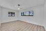 Wood-finish flooring with white baseboards, white walls, and a modern ceiling fan