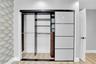Integrated closet system featuring light-toned sliding panel doors, internal shelving, and hanging rods