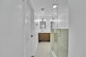 Glass-enclosed shower with gold-tone hardware, wood-finish vanity with white countertop, arched mirrors, and wall-mounted light fixtures