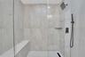 Walk-in shower featuring a built-in bench, glass enclosure, matte black fixtures, and herringbone-patterned floor tile