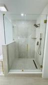Glass-enclosed shower featuring a rain shower head, hand-held shower, tiled walls, a built-in shelf, and a patterned tile floor