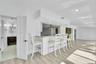 Integrated breakfast bar with a light-toned countertop, recessed lighting, wood-finish flooring, white paneled doors, and a bathroom featuring a vanit